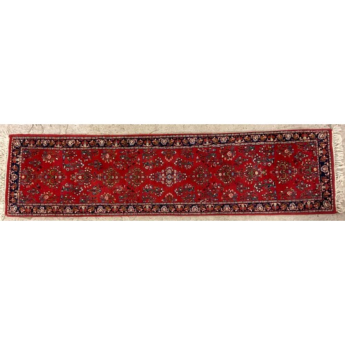 406 - A Middle Eastern woollen runner, with stylised flowers and scrolls, banded borders red ground, 267cm... 