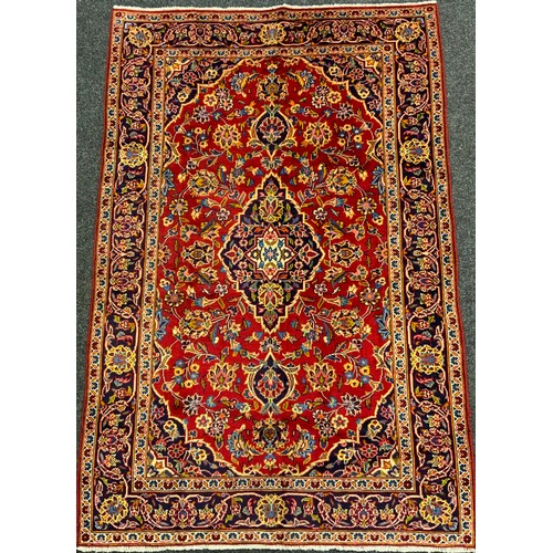 61 - A Kashan rug / carpet, hand-knotted in rich tones of red, cream, indigo, and blue, 202cm x 134cm.