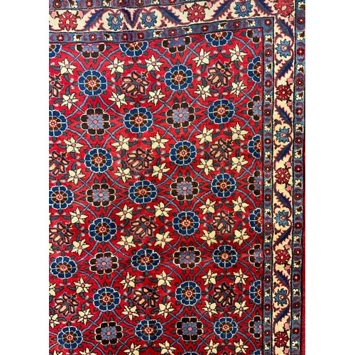 85 - A mid 20th century Persian Veramin rug / carpet, hand-knotted in rich red, with a field of blue, whi... 