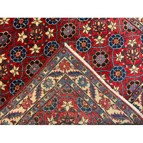 85 - A mid 20th century Persian Veramin rug / carpet, hand-knotted in rich red, with a field of blue, whi... 