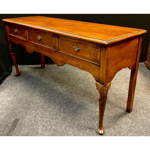 111 - A George III style reproduction cross-banded oak dresser base / sideboard, over-sailing top, three s... 