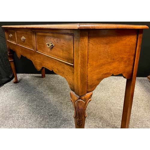 111 - A George III style reproduction cross-banded oak dresser base / sideboard, over-sailing top, three s... 