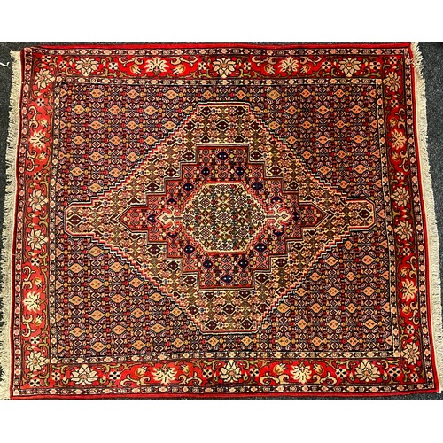 133 - A Senneh rug / carpet, knotted in red, burgundy, coral, and deep indigo, with a hexagonal medallion ... 