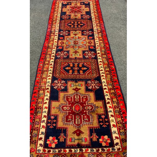 135 - An Azerbaijan runner carpet, hand-knotted in red, cream, and deep blue, 332cm x 109cm.