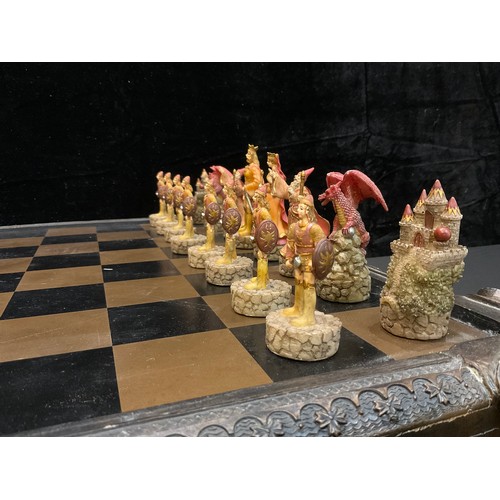 23 - A novelty chess set, the resin pieces as myth and magic figures, the chess board with a pair of stor... 