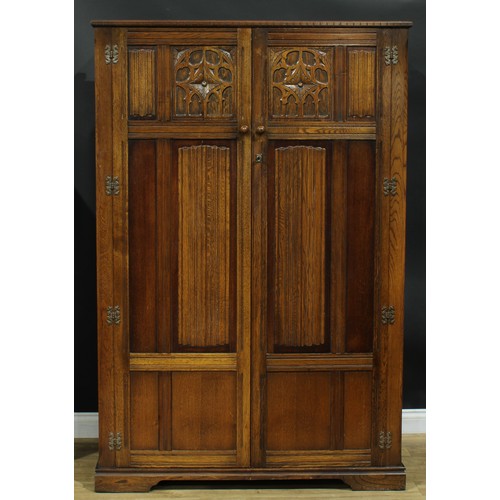 320 - An oak bedroom suite, Gothic Revival style and linenfold elements, comprising wardrobes 185.5cm wide... 