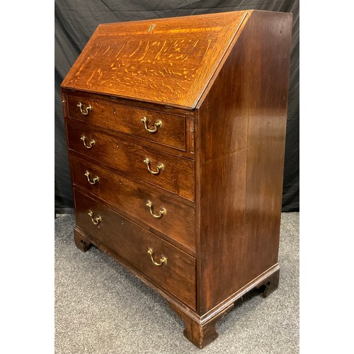 135 - A George III oak bureau, the fall front enclosing an arrangement of small drawers, pigeon holes and ... 