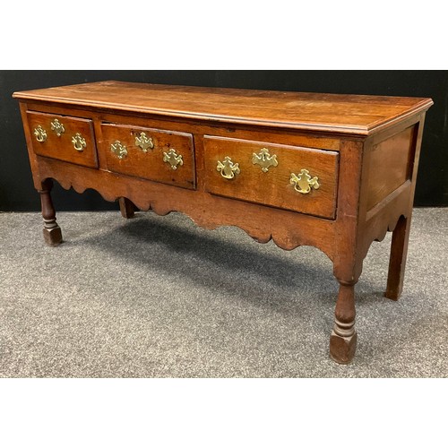 131 - A George III oak dresser base, over-sailing top, three short drawers to frieze, shaped apron, turned... 