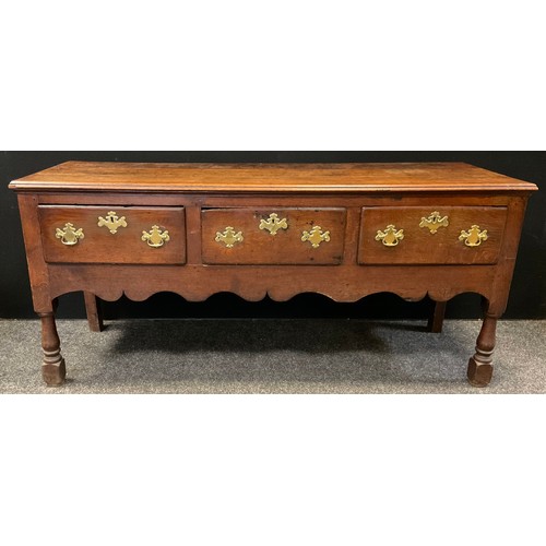 131 - A George III oak dresser base, over-sailing top, three short drawers to frieze, shaped apron, turned... 