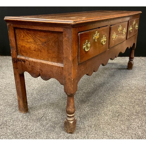 131 - A George III oak dresser base, over-sailing top, three short drawers to frieze, shaped apron, turned... 