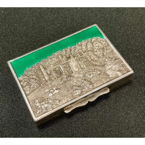 92 - A silver and enamel rectangular  snuff box, the cover embossed with  Haddon Hall, picked out in gree... 