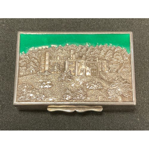 92 - A silver and enamel rectangular  snuff box, the cover embossed with  Haddon Hall, picked out in gree... 