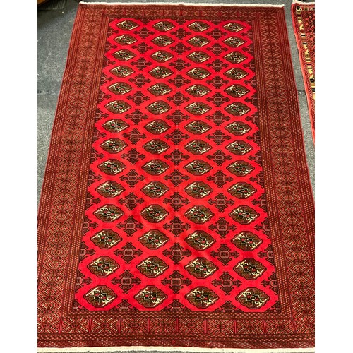 225 - A Turkoman rug / carpet, knotted in rich red, with a multi medallion field, wide stylised geometric ... 