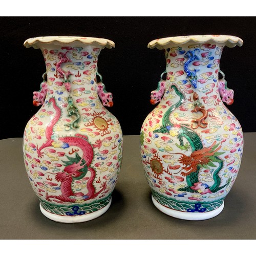 203 - A pair of Chinese Famille rose vases, decorated with dragons, dogs-of-foe and clouds, shi-shi handle... 