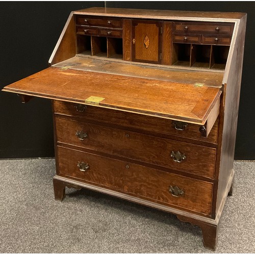 184 - A George III inlaid oak bureau, the fall front with Swan patera, enclosing an arrangement of small d... 