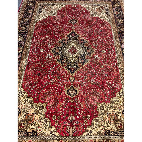 212 - A Persian Tabriz rug/carpet, central medallion within intricate floral field in tones of red, cream,... 