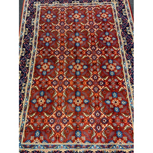 594 - A Persian Mashad hand-knotted rug / carpet, having a central field in rich red and Lapis blue, with ... 