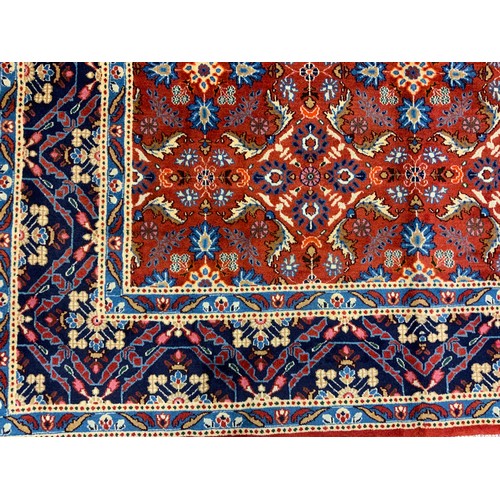 594 - A Persian Mashad hand-knotted rug / carpet, having a central field in rich red and Lapis blue, with ... 