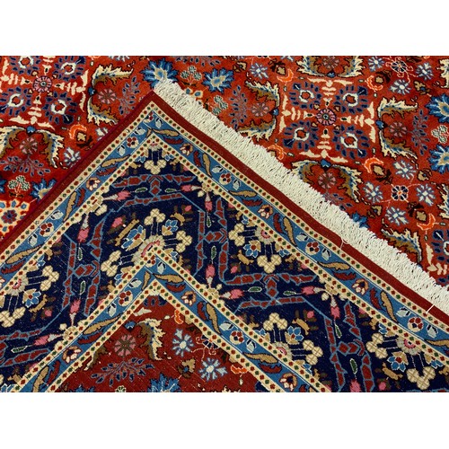 594 - A Persian Mashad hand-knotted rug / carpet, having a central field in rich red and Lapis blue, with ... 