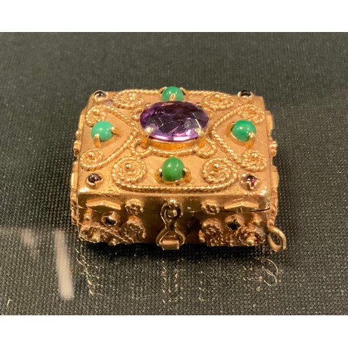 716 - An amethyst and green stone and garnet cabochon mounted gold coloured metal pill box, wirework scrol... 