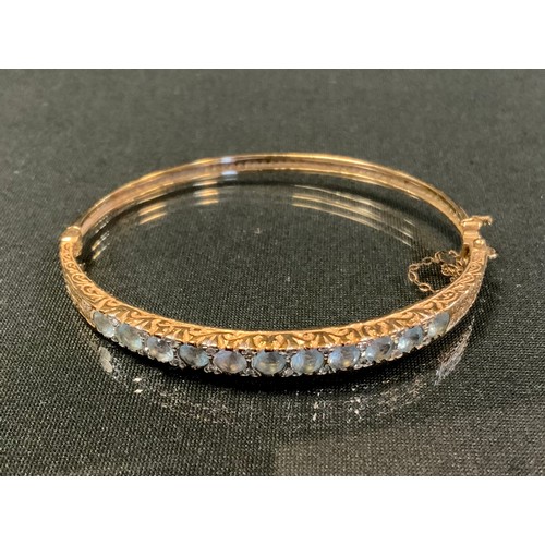 726 - An Edwardian diamond and aquamarine hinge bangle, inset with eleven old round cut aquamarines each d... 