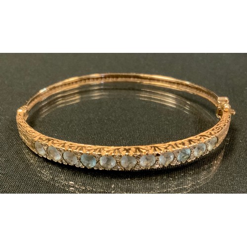 739 - An Edwardian diamond and aquamarine hinge bangle, inset with eleven old round cut aquamarines each d... 