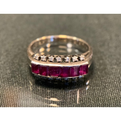 741 - A ruby and diamond ring, set with six pinky red baguette cut rubies, between sixteen individually mo... 