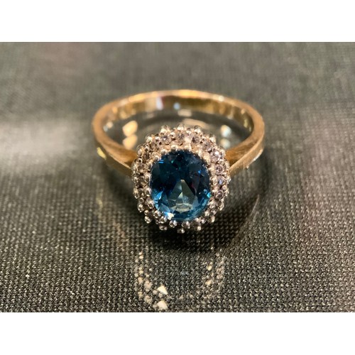 749 - A diamond and blue topaz ring, central oval vibrant pale blue topaz approx 0.75ct surrounded by twen... 