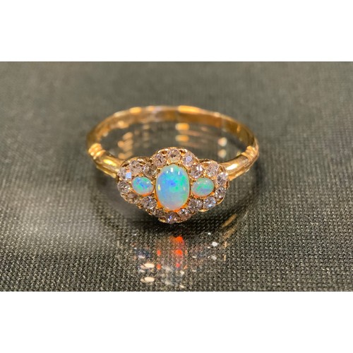 756 - A diamond and opal cluster ring, with three oval opals flashing green, red and violet colour, surrou... 