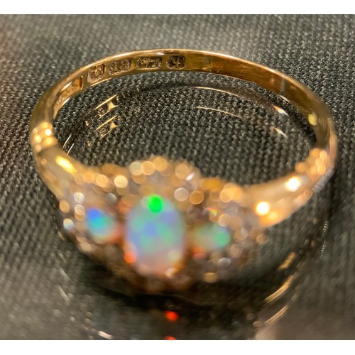 756 - A diamond and opal cluster ring, with three oval opals flashing green, red and violet colour, surrou... 