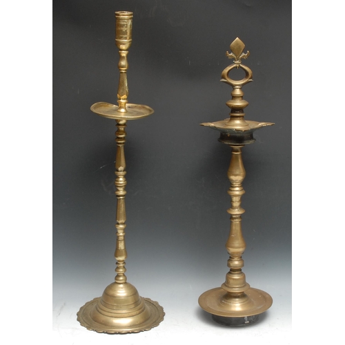 696 - A large Indian brass candlestick, cylindrical sconce above a broad drip pan, domed lotus shaped base... 