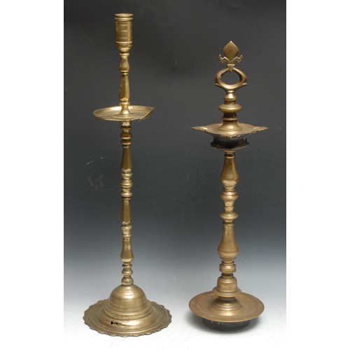 696 - A large Indian brass candlestick, cylindrical sconce above a broad drip pan, domed lotus shaped base... 