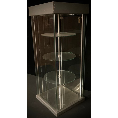 827 - A three tier revolving glass counter top display case, two interior lights, 76.5cm high