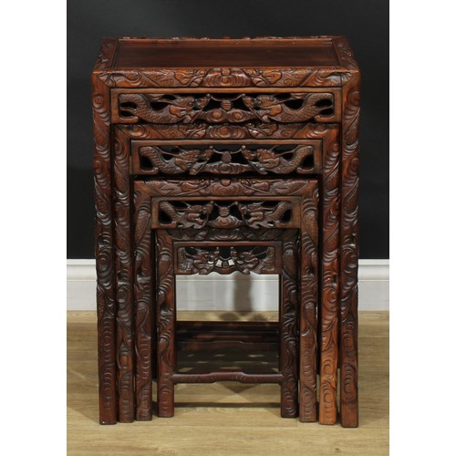 1117 - A set of Chinese hardwood quartetto tables, rectangular panel tops, the borders carved with ferociou... 