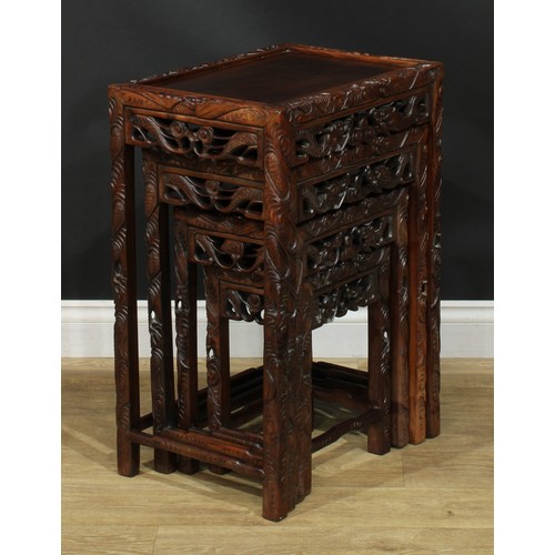 1117 - A set of Chinese hardwood quartetto tables, rectangular panel tops, the borders carved with ferociou... 