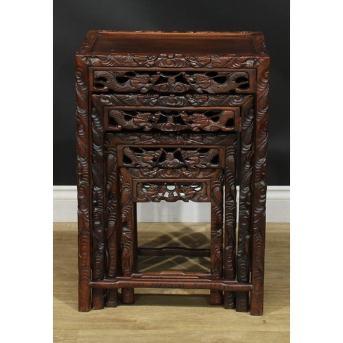 1117 - A set of Chinese hardwood quartetto tables, rectangular panel tops, the borders carved with ferociou... 