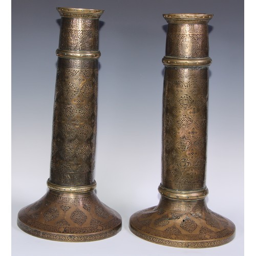 1191 - A pair of large Middle Eastern Islamic brass mosque candlesticks, pierced and engraved with a field ... 