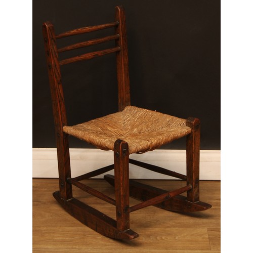 1003 - A 19th century vernacular elm rocking chair, of primitive pegged construction, the back with three h... 