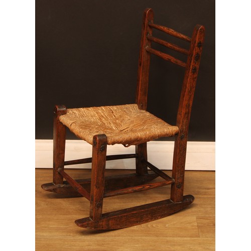 1003 - A 19th century vernacular elm rocking chair, of primitive pegged construction, the back with three h... 