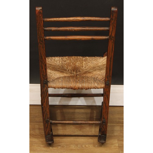 1003 - A 19th century vernacular elm rocking chair, of primitive pegged construction, the back with three h... 