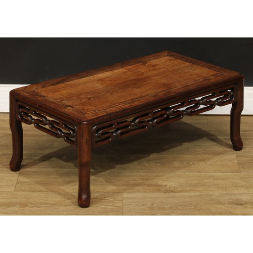 1031 - A Chinese hardwood kang or low tea table, rounded rectangular panelled top above a carved and pierce... 