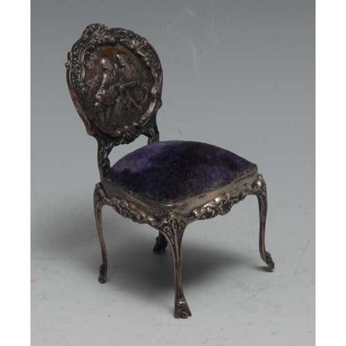 195A - An Edwardian silver miniature pincushion chair, as a Rococo salon chair, the back embossed with a co... 