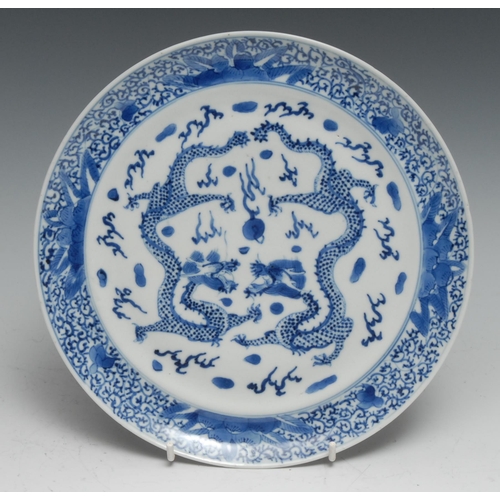 742 - A Chinese circular dish, painted in tones of underglaze blue with dragons chasing a flaming pearl, 2... 