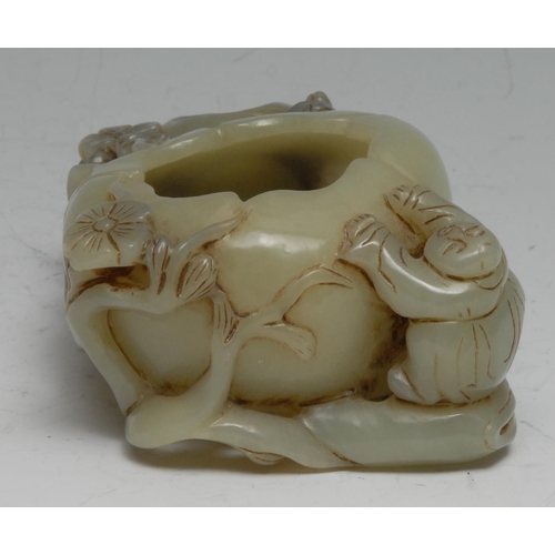 740 - A Chinese celadon jade brush washer, carved with a figure and blossom alongside a peach, 11cm wide