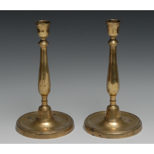 1266 - A pair of 18th century French brass table candlesticks, of seamed construction, dished circular base... 