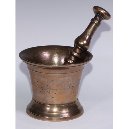 1141 - An 18th century bronze pestle and mortar, flared rim, skirted base, the mortar 14cm high, the pestle... 