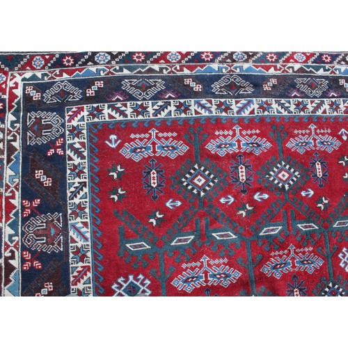 847 - A Middle Eastern rectangular wool rug or carpet, the field worked with hooked medallions and geometr... 