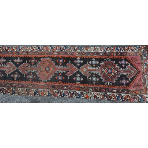 848 - A Middle Eastern wool runner rug, rectangular field worked with hooked medallions, banded borders wi... 