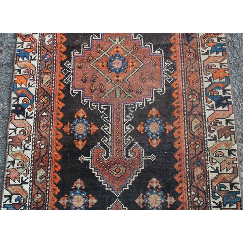 848 - A Middle Eastern wool runner rug, rectangular field worked with hooked medallions, banded borders wi... 