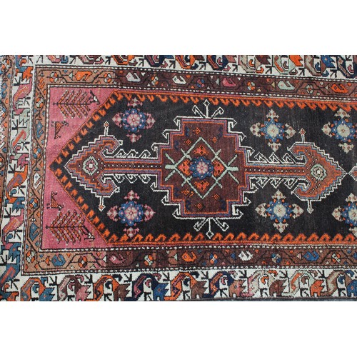 848 - A Middle Eastern wool runner rug, rectangular field worked with hooked medallions, banded borders wi... 